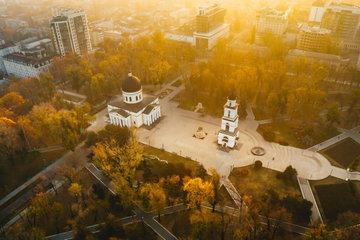 A birds-eye view shot of two pretty black and white monasteries in Moldova, set within a courtyard surrounded by autumnal trees