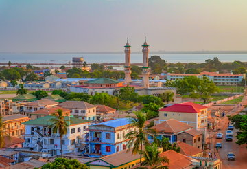 Aerial view of a seafront town, with a mosque’s minarets towering above the surrounding colourful buildings on an overcast evening, Banjul, Gambia, Africa