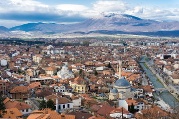 A wide angle shot of Pizren in Kosovo, a busy city with terracotta roofs with an impressive mountain backdrop with low-lying clouds