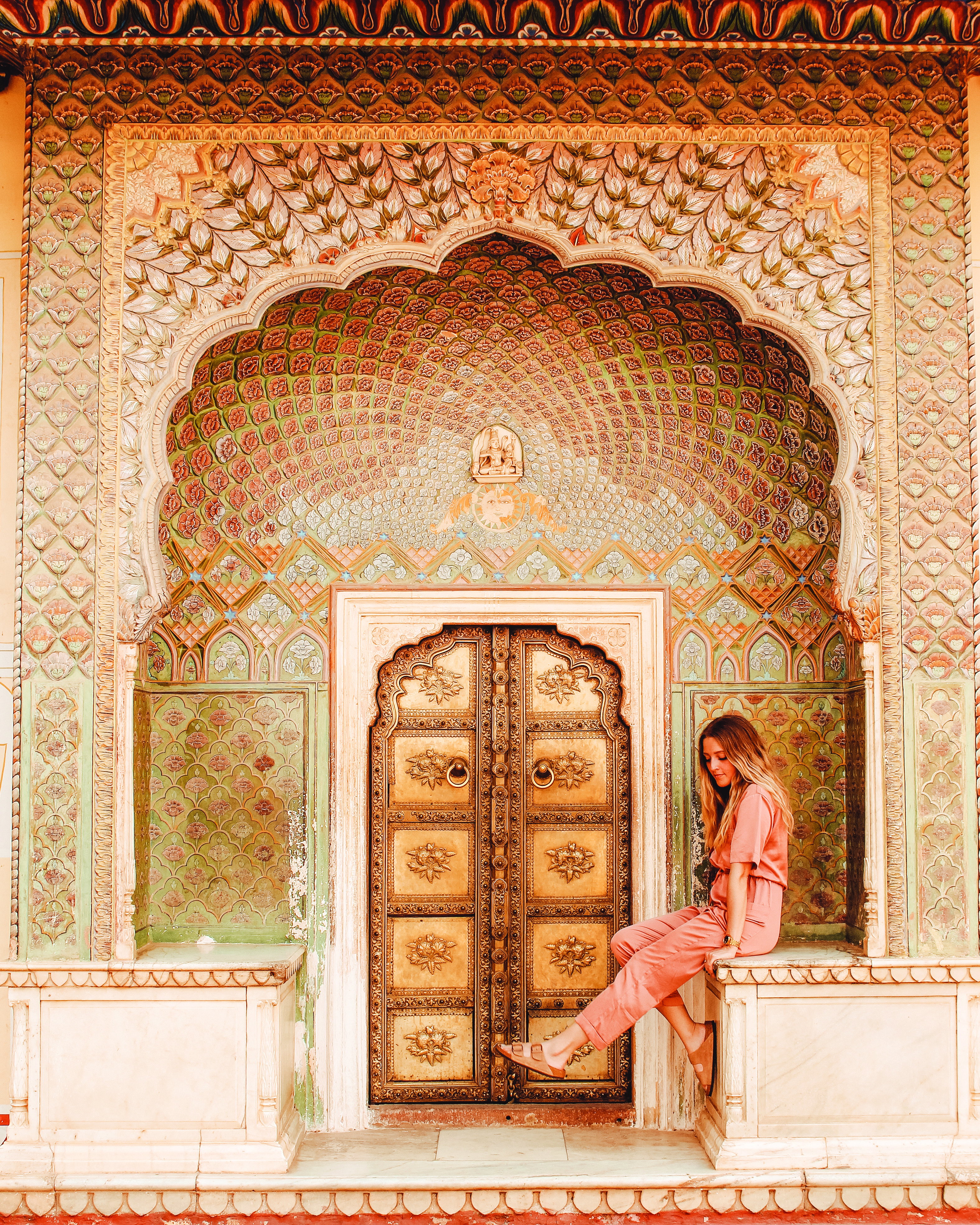 A lady poses in one of the beautiful ornate archways, that a decorated with bronze tiles at Jantar Mantar, Jaipur, India