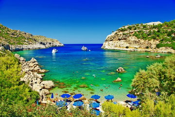 Two boats sit in a beautiful bay lined with rocky cliffs in Rhodes, Greece