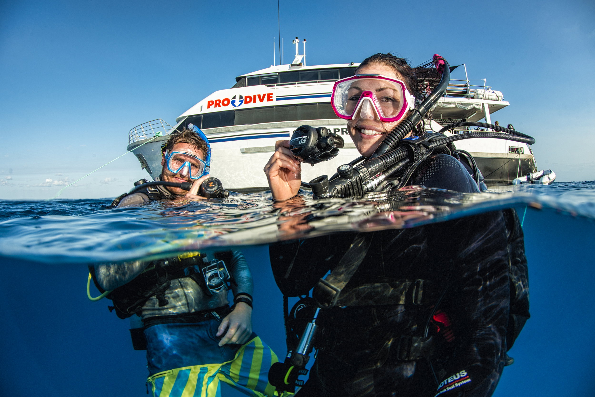 Scuba divers in the ocean in front of a boat, on 2 Night Outer Barrier Reef Liveaboard Diving Cruise, Cairns, Australia.