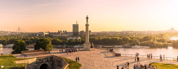 Pobednik Monument surrounded by people, overlooking the Danube River and the city of Belgrade in Serbia