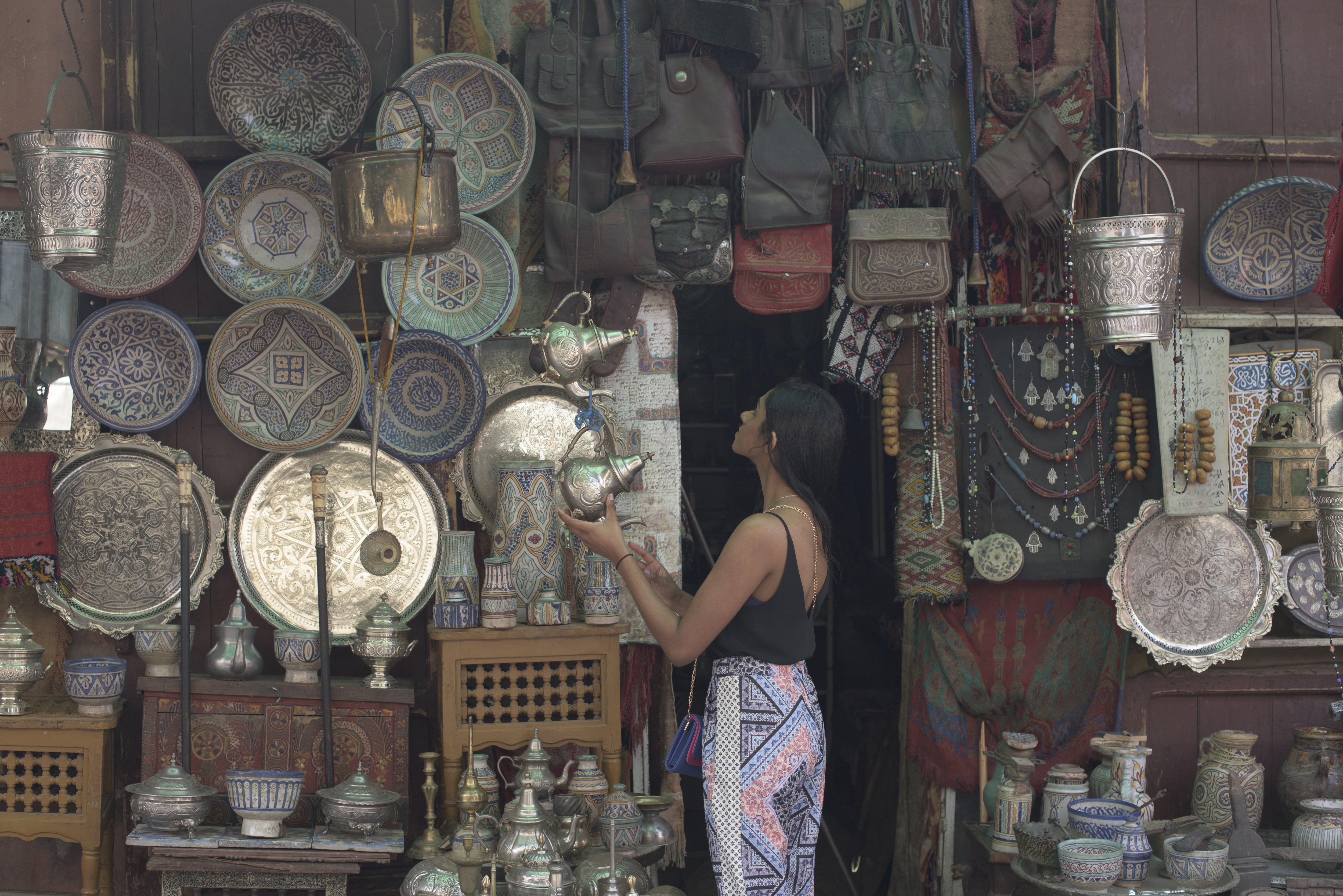 A young woman at a local shop in Marrakech exmaines the amazing array of ornamental plates and bags hanging from the wall. 