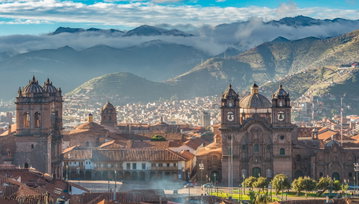 The grand Church of the society of Jesus at Cusco’s Plaza de Armas with the terracotta buildings of Cusco and the Andes Mountains behind