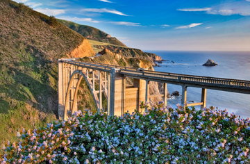 Wide angle shot pf Bixby Bridge California, USA, sitting high above the ocean winding its way into the hills in the distance on a bright sunny day.