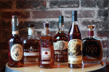Row of Kentucky bourbon bottles in front of a brick wall