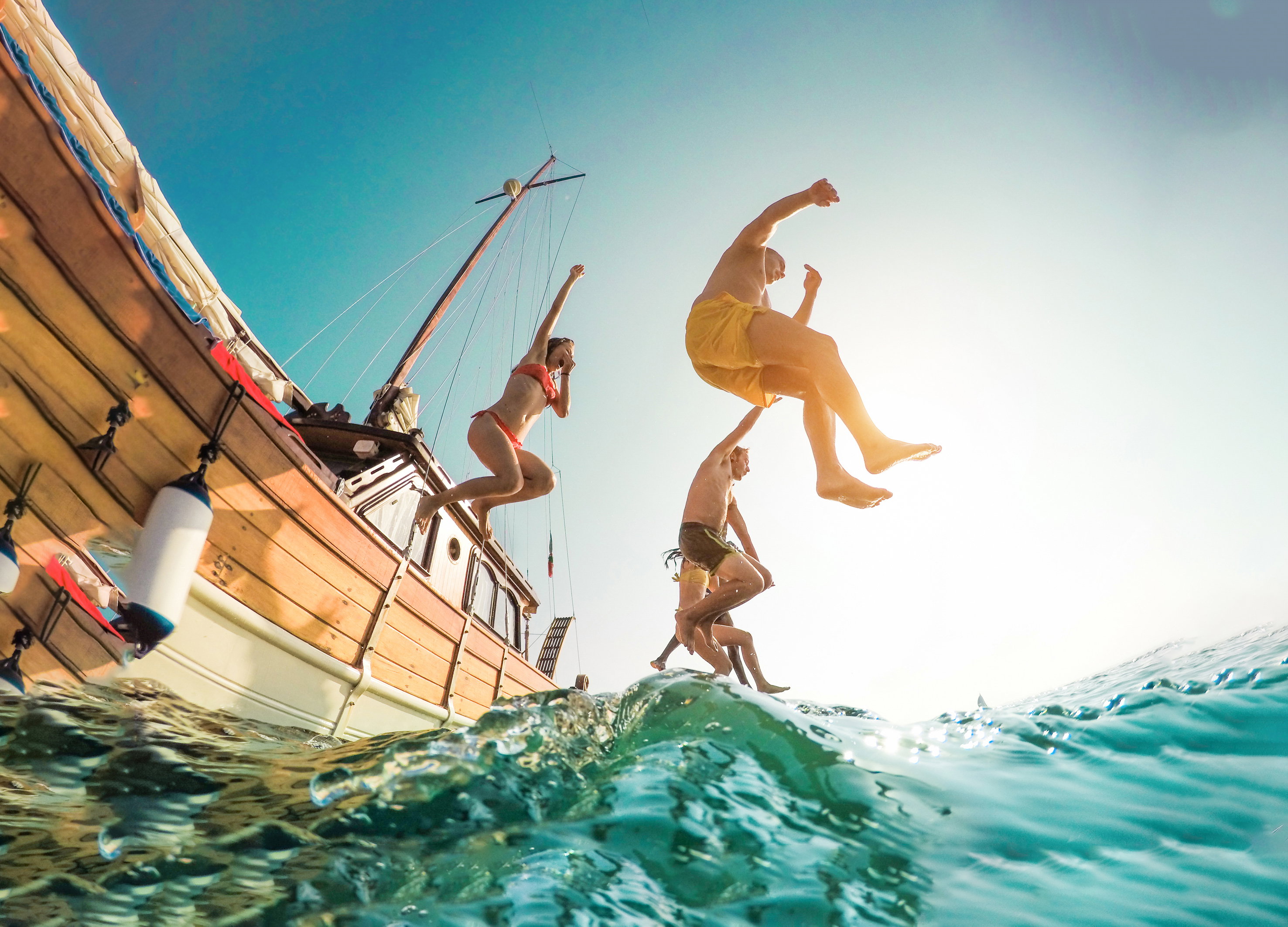Friends jumping from boat into the sea