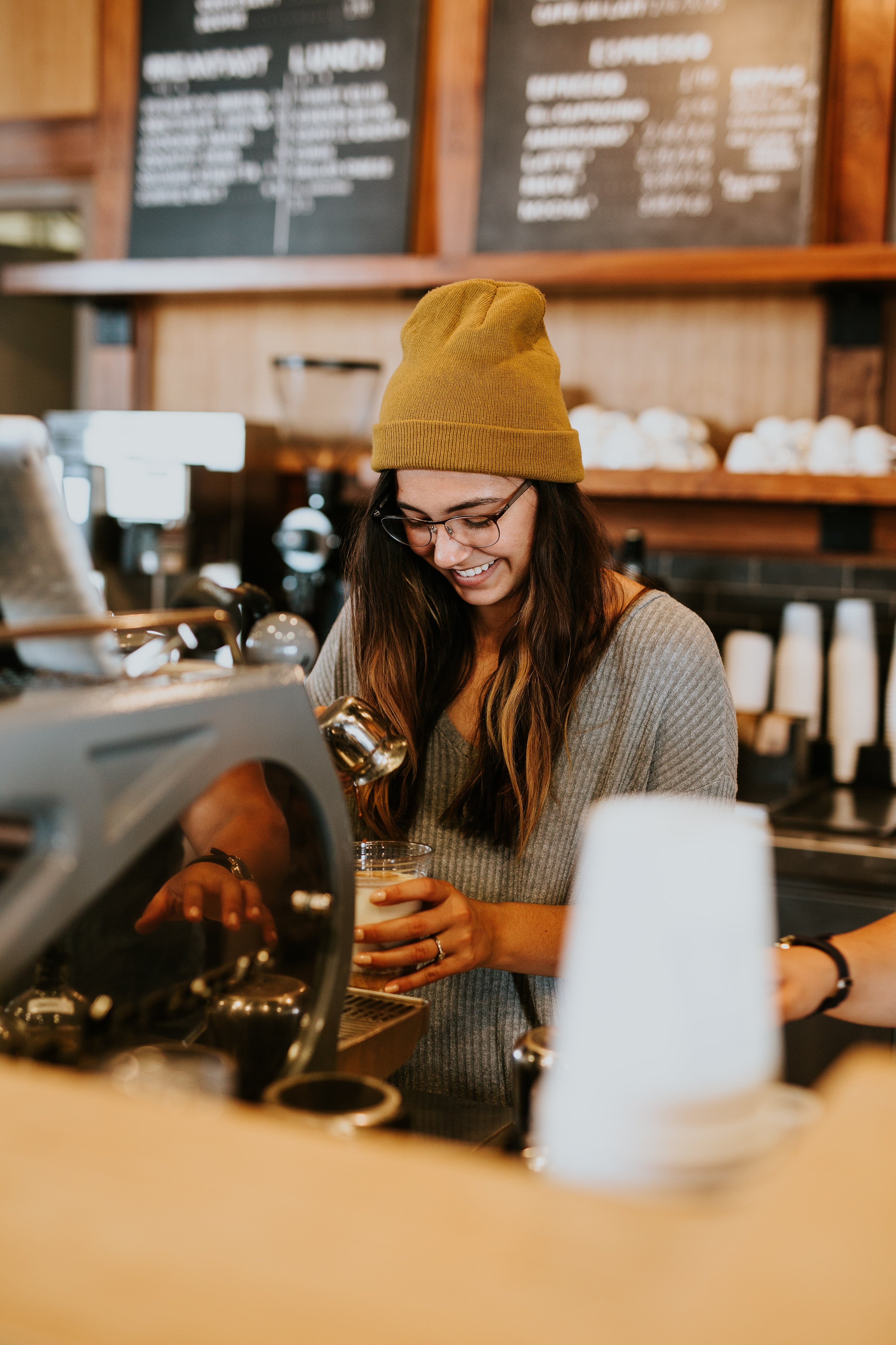 Young smiling woman barrista working in a café preparing coffee