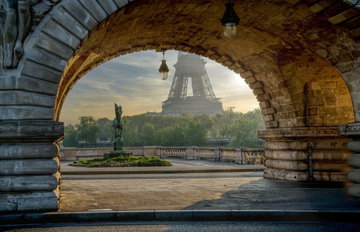 Peek view of Eiffel Tower through an arch in Paris, France
