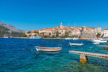 Red roofed buildings sit on a hilltop overlooking the coast in Korcula, Croatia