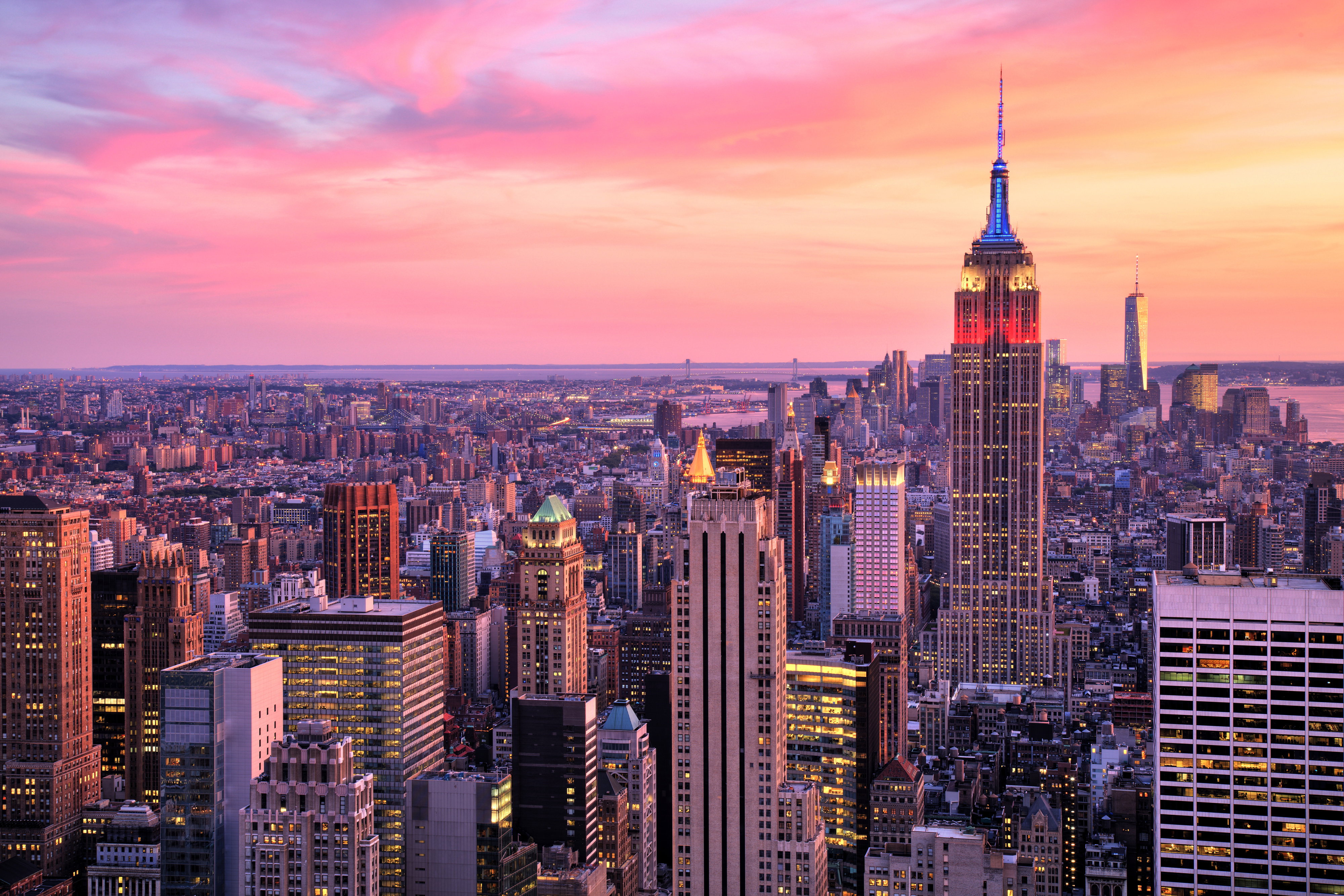 Urban skyline at dusk, with the Empire State Building glowing blue and the Hudson River beyond in New York City, USA