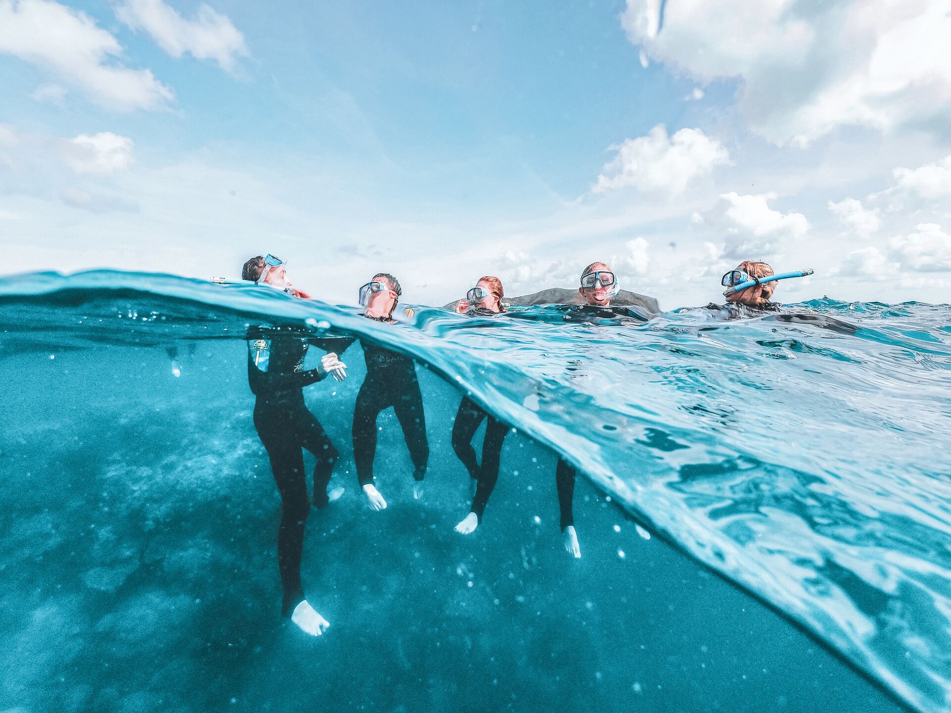 A group of young people wearing snorkelling equipment take to the crystal clear waters of the Great Barrier Reef 