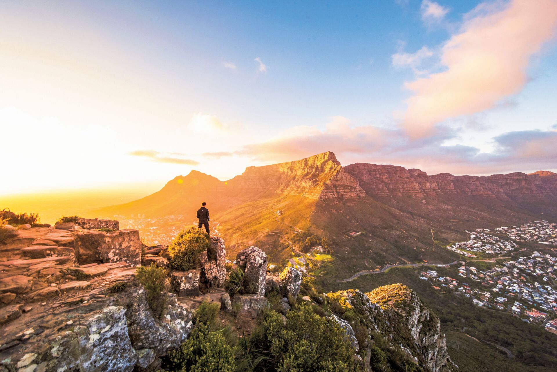 A young man atop of a cliff with the Table Mountain in view, Cape Town, South Africa