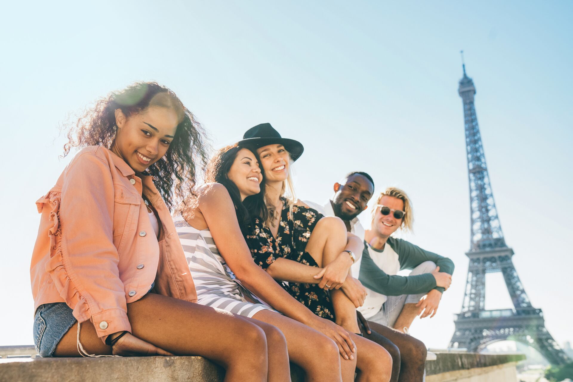 A group of travellers sitting on the wall with a backdrop of the Eiffel Tower in Paris, France