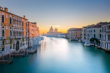 The Venice canal dotted with boats and lined either side by elegant colourful palazzi, Italy