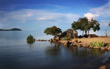 Picturesque views of the ocean and a small island of boulders and African trees in Malawi, Africa. 