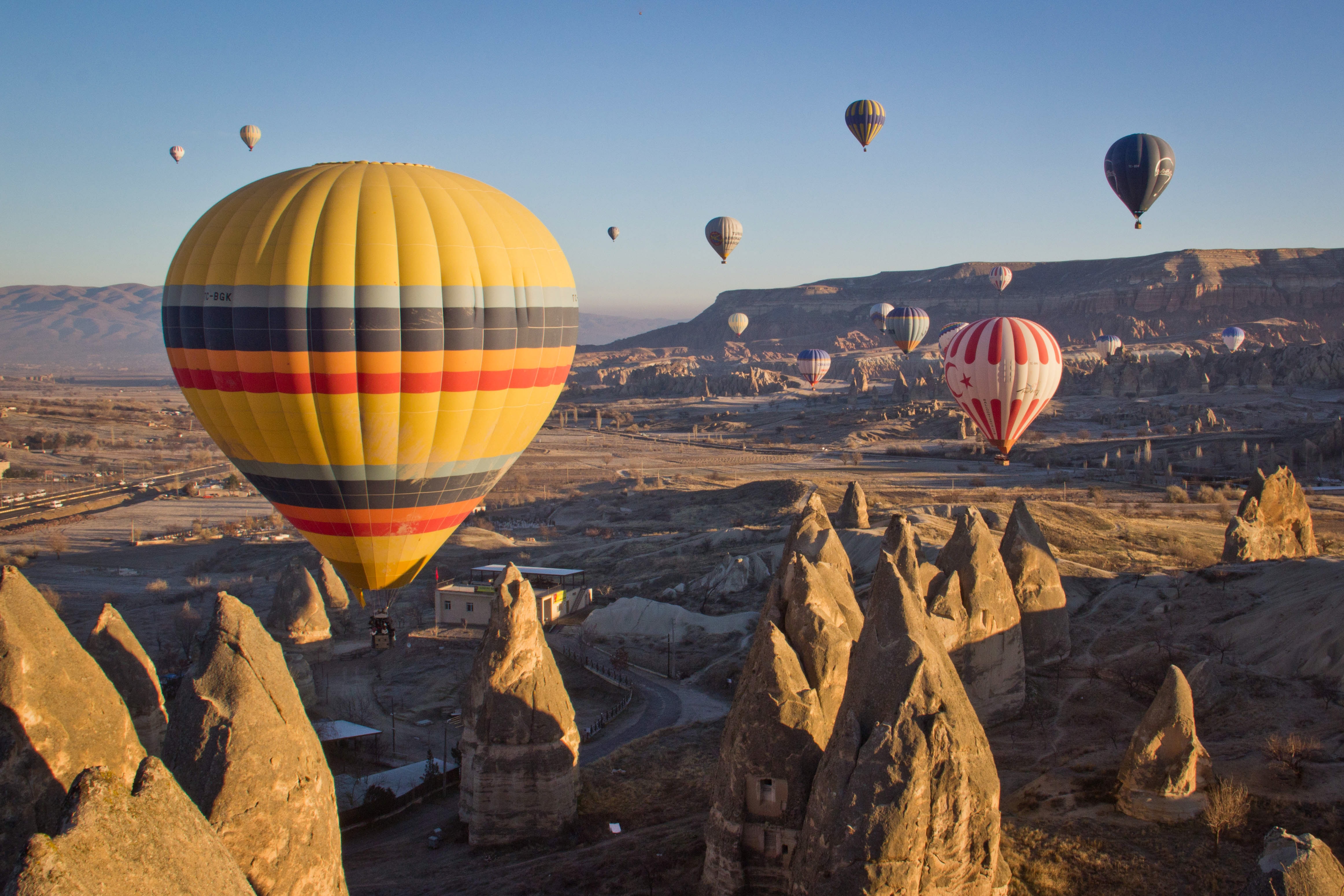 Colourful hot air balloons flying above the unusual rock formations of the Cappadocia valley, Turkey at sunrise.