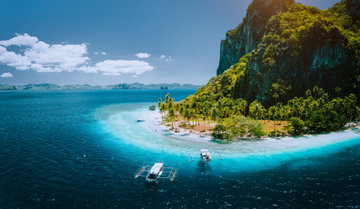 Aerial drone picture of tourist boats arriving tropical Pinagbuyutan Island with idyllic ipil beach. El Nido