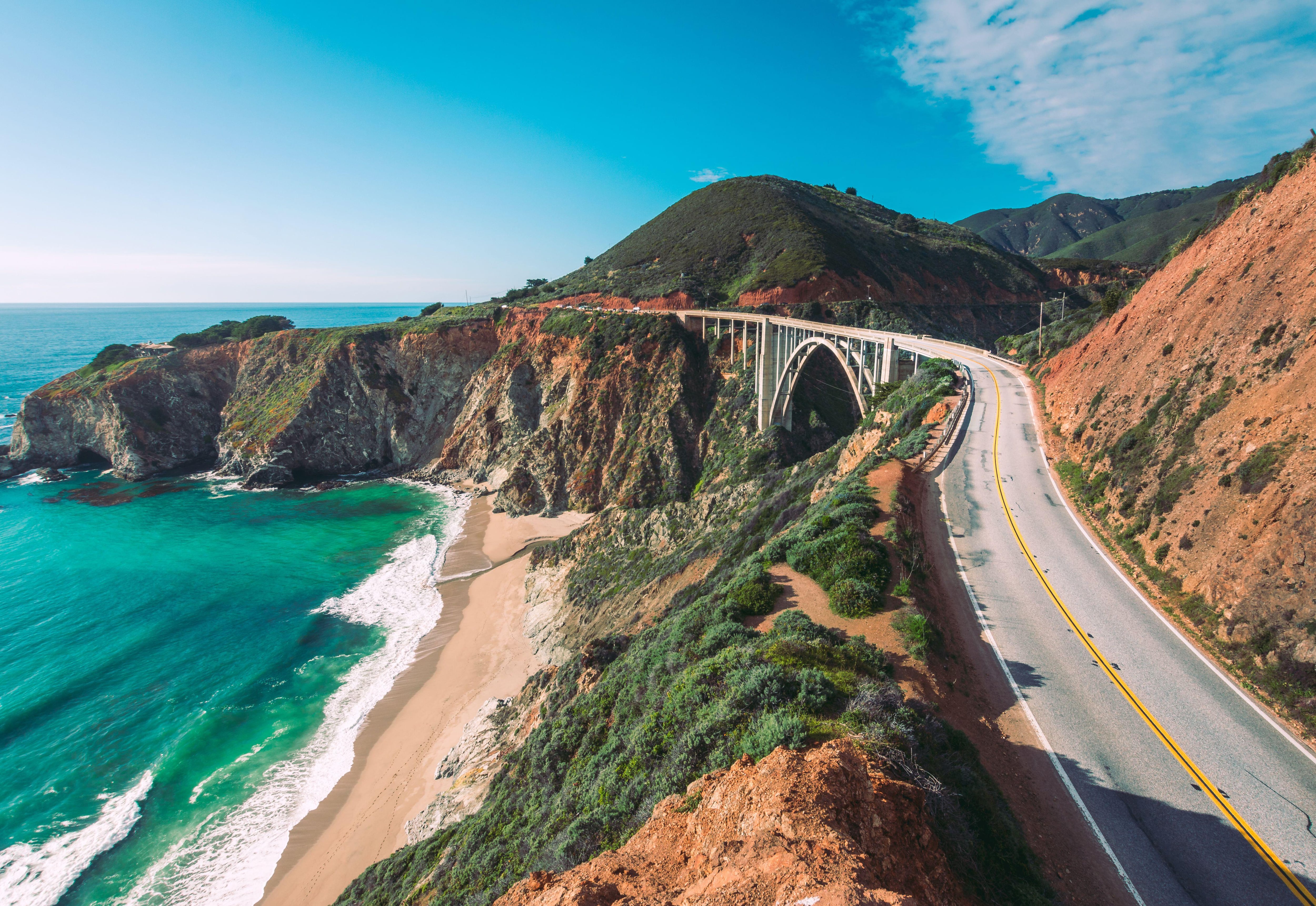 The winding road of California’s Highway 1 runs alongside the Pacific Ocean, beneath the cliff is a sandy beach