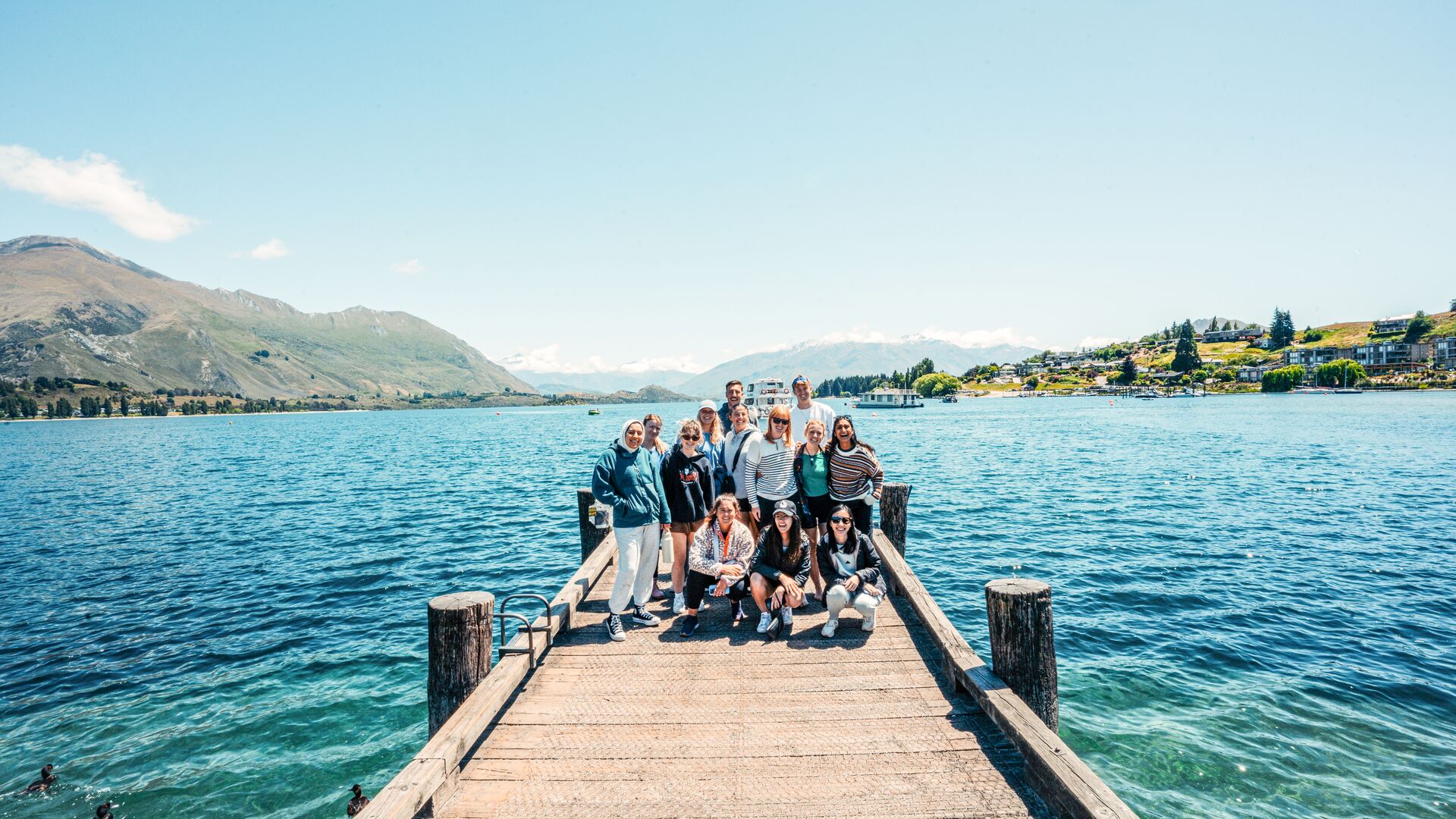 A group of travellers posing for the camera at the end of the jetty in Lake Taupo in New Zealand