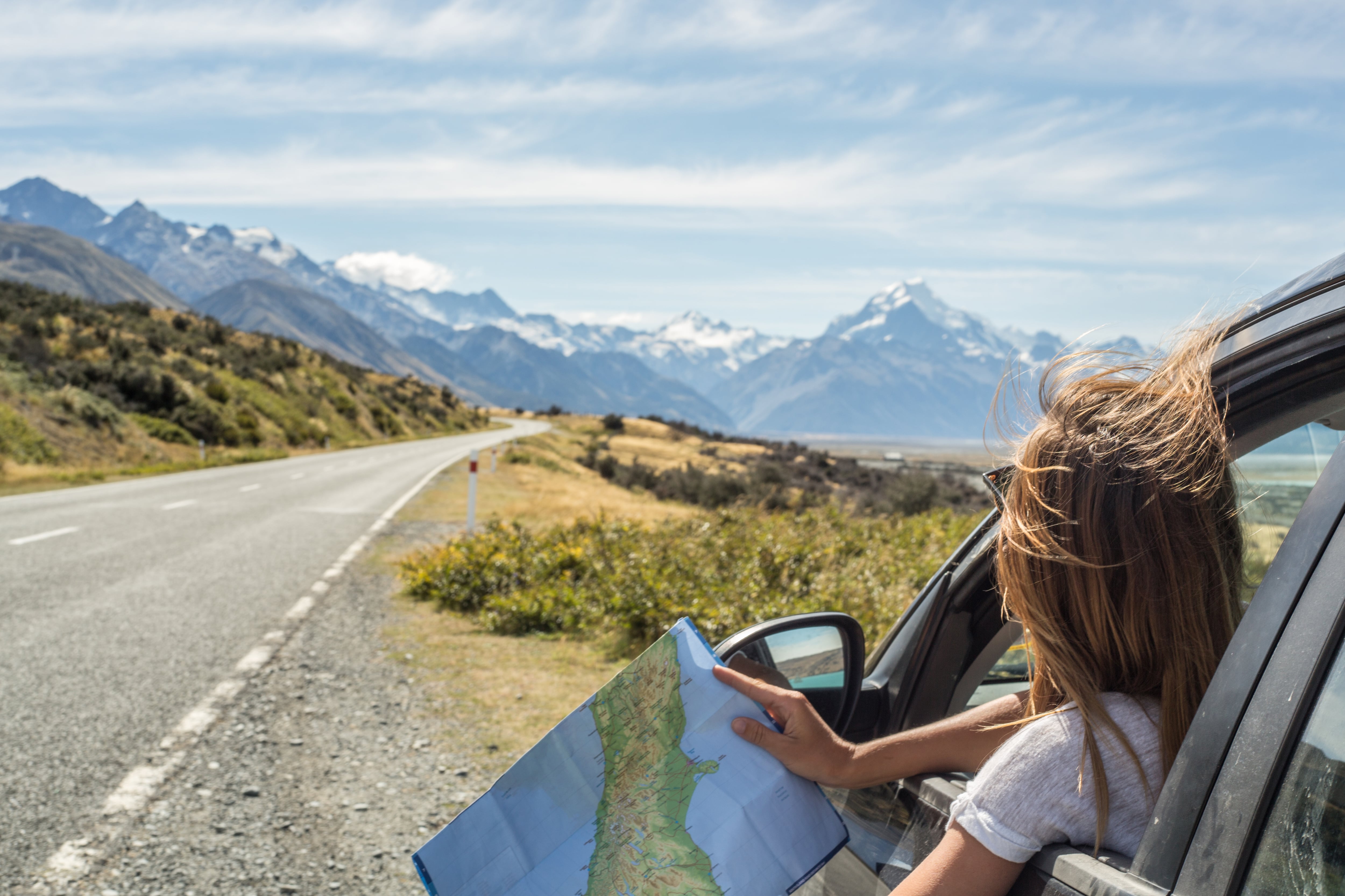 Portrait of a young woman in a car looking at a map for directions, Mount Cook, New Zealand