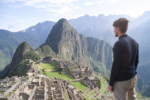 Young man standing and looking at the amazing Machu Picchu, Peru, South America