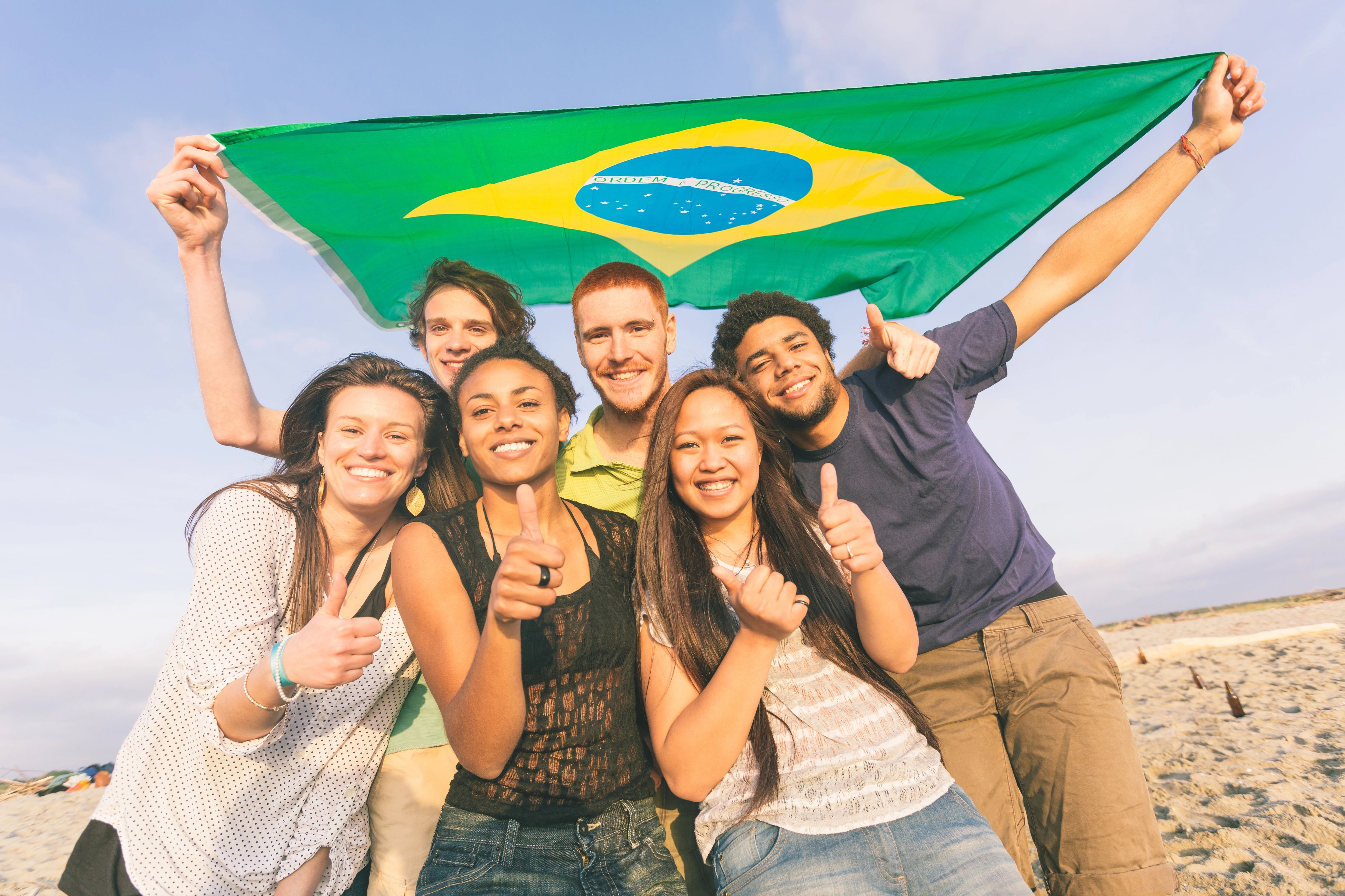 Friends with a Brazilian flag on a beach