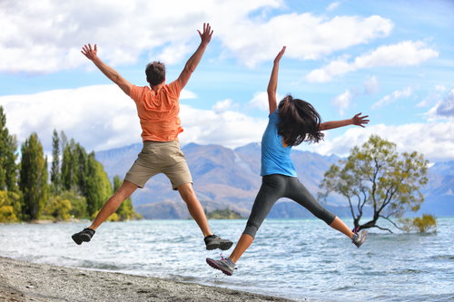 New Zealand tourists couple jumping at Wanaka Tree, South Island, New Zealand