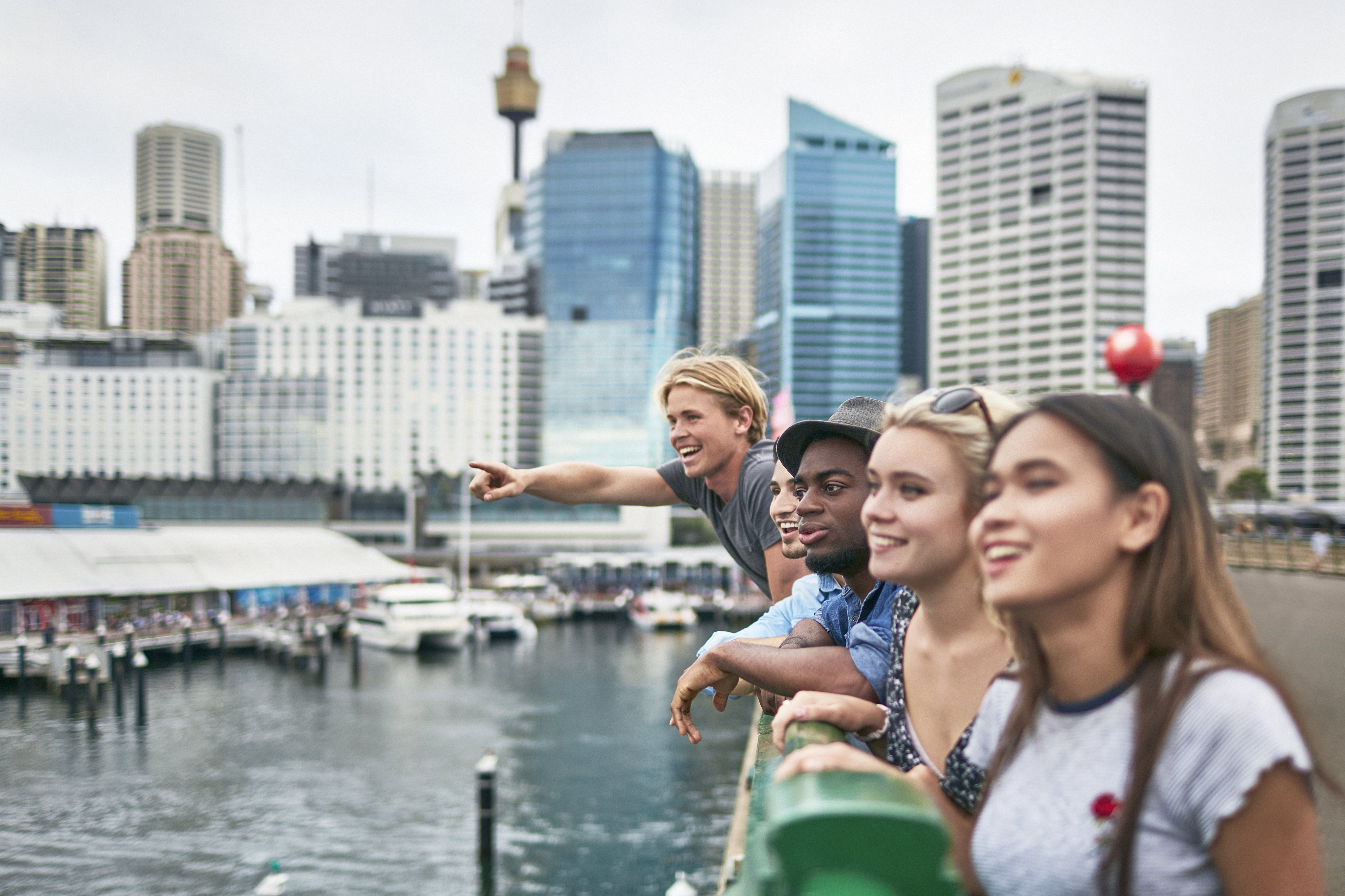 Excited friends looking away against buildings, Sydney, Australia