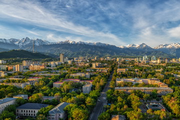 Aerial view of the central part of the city of Almaty against the background of the Zailiyskiy Alatau mountains in an early spring morning, Kazakhstan