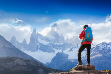 Active hiker hiking, enjoying the view, looking at Patagonia mountain landscape.