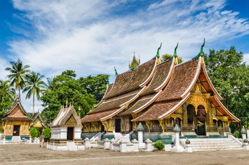 Wat Xieng Thong, a beautiful Buddhist temple with a sloped roof that almost reaches the floors and doors decorated with gold stencilling, in Luang Prabang, Laos