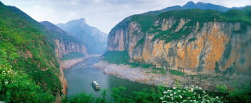 A cruise ship sits on the Yangtze River, China, dwarfed by the enormous rock canyon walls lining the river