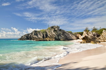 Turquoise waters lap a white sand beach surrounded by dramatic granite rocks in Bermuda