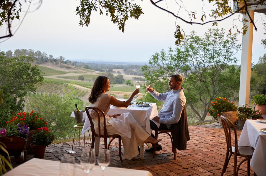 Couple enjoying Swift Sparkling Wine and oysters with scenic views across Printhie Wines vineyard , Australia