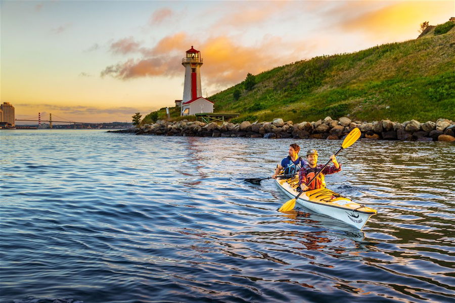 A couple at a lighthouse at sunset in Nova Scotia, Canada