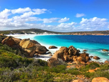 A wide angle view of the blue sea, surrounded by white sand and rugged cliffs, Western Australia