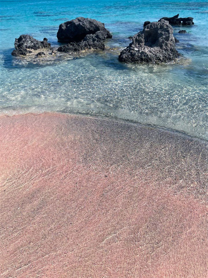 Water lapping onto the pink sand beach in Crete, Greece