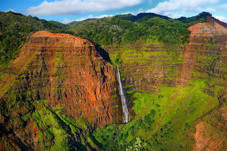 A narrow waterfall cascades down Waimea Canyon in Hawaii