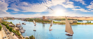 Traditional Feluccas floating on the River Nile on a sunny day in Aswan, Egypt.