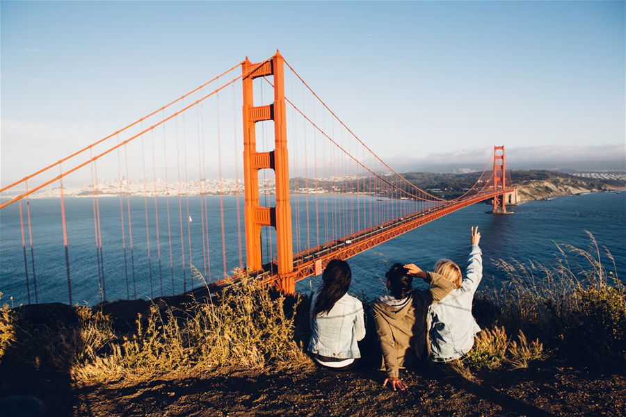 Friends sitting in San Francisco looking at Golden Gate Bridge, United States