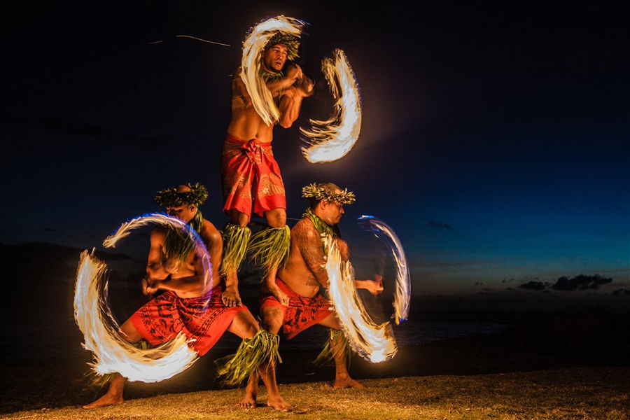 Fire dancers twirling flames at night on a beach in Hawaii