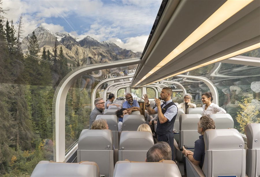 Passengers in a train carriage with a glass roof as it passes through the Rocky Mountains in Canada