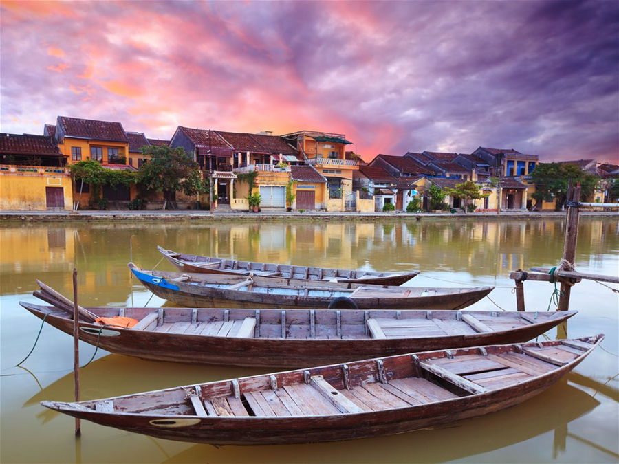 View of the old town from the river with boats in the foreground during twilight hours in Hoi An, Vietnam