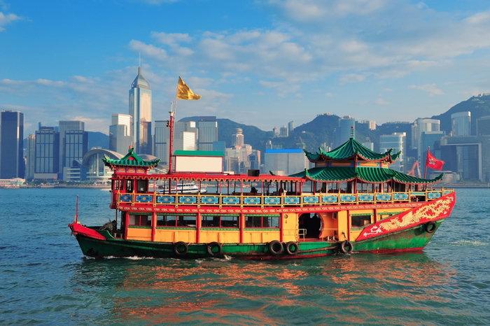 Colourful boat against the city skyline in Victoria Harbour, Hong Kong.