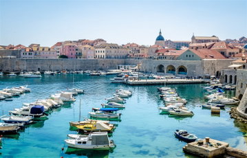Rows of boats sit in the harbour against the old walls of Dubrovnik, Croatia