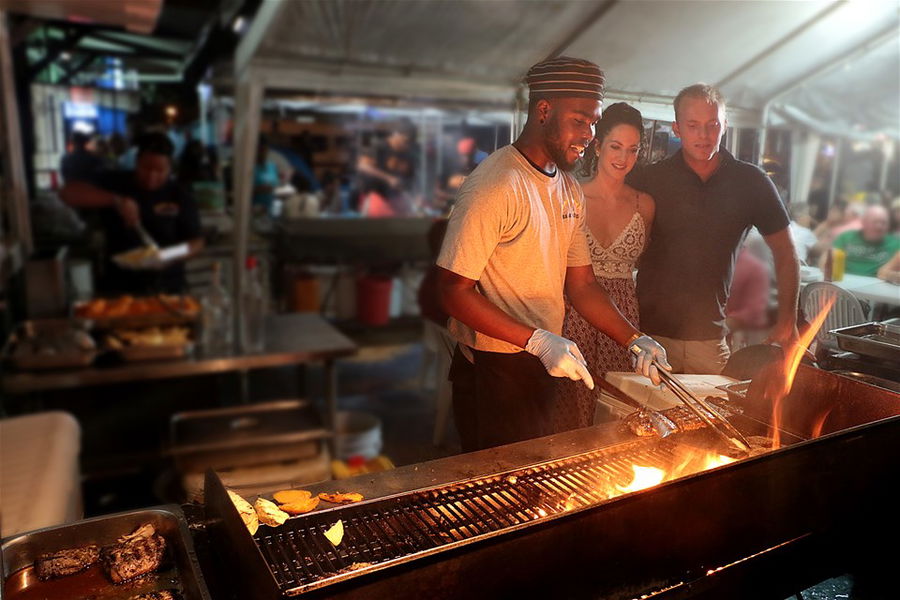 A couple look at fish being cooked at BBQ Oistins Fish Fry Barbados