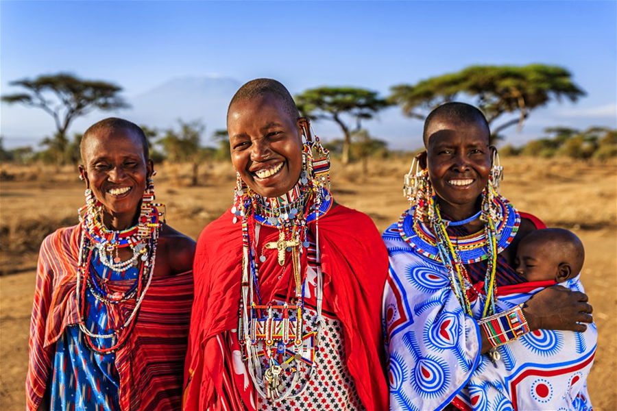 Mother from the Maasai tribe carries her baby as she poses with her happy family in Kenya, Africa