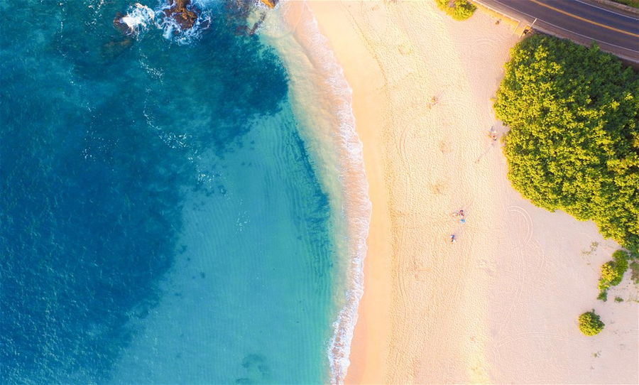 An aerial view of a white sand beach lapped by turquoise waters in Hawaii